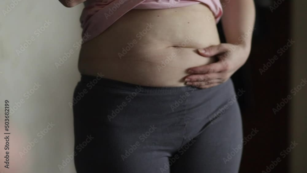 overweight, a woman in the mirror looks at her fat belly