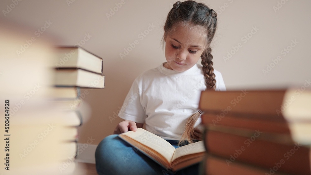 little girl in the library reading a book. education school kid science concept. a child sits on the floor stacks of books flips through the pages reads studies. daughter reading a lifestyle book little girl in the library reading a book. education school kid science concept. a child sits on the floor stacks of books flips through the pages reads studies. daughter reading a lifestyle book