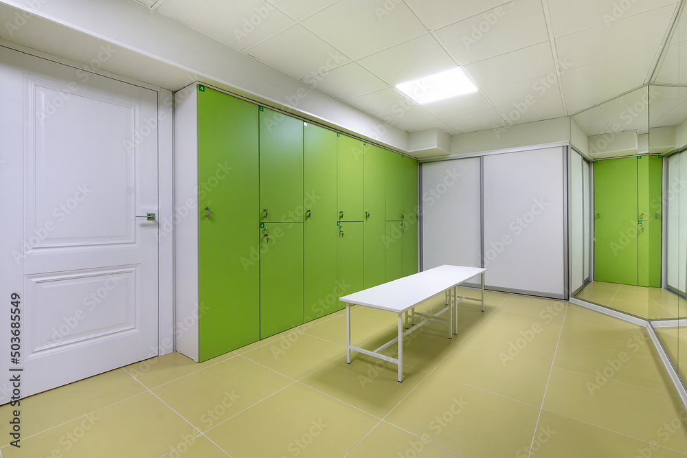 A bright locker room in the wellness center with a white entrance door, light green lockers. A bright locker room in the wellness center with a white entrance door, light green lockers.