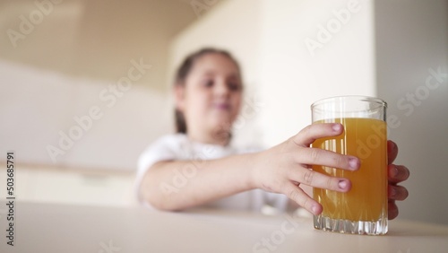 girl child drinking juice. happy family a healthy eating kid dream concept. daughter girl drinking yellow juice from a glass cup in the kitchen. child indoors drinking fruit juice