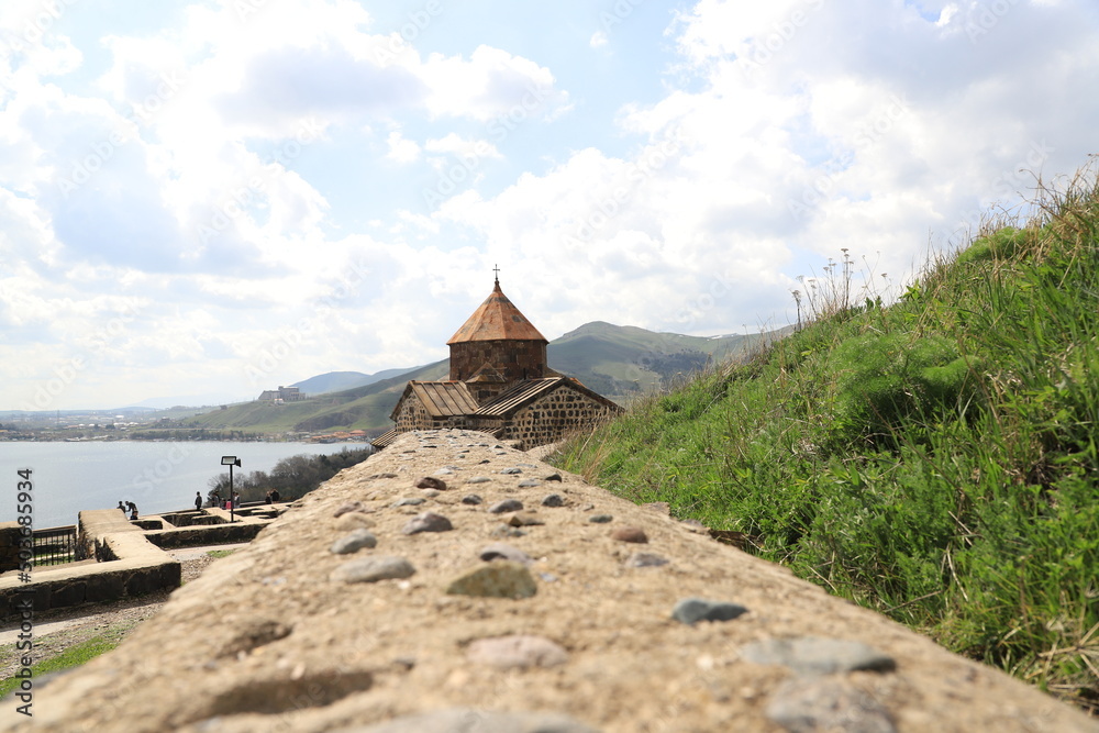 One of the temples in the ancient Sevanavank monastery on Lake Sevan in Armenia and part of the monastery wall leading to the temple.