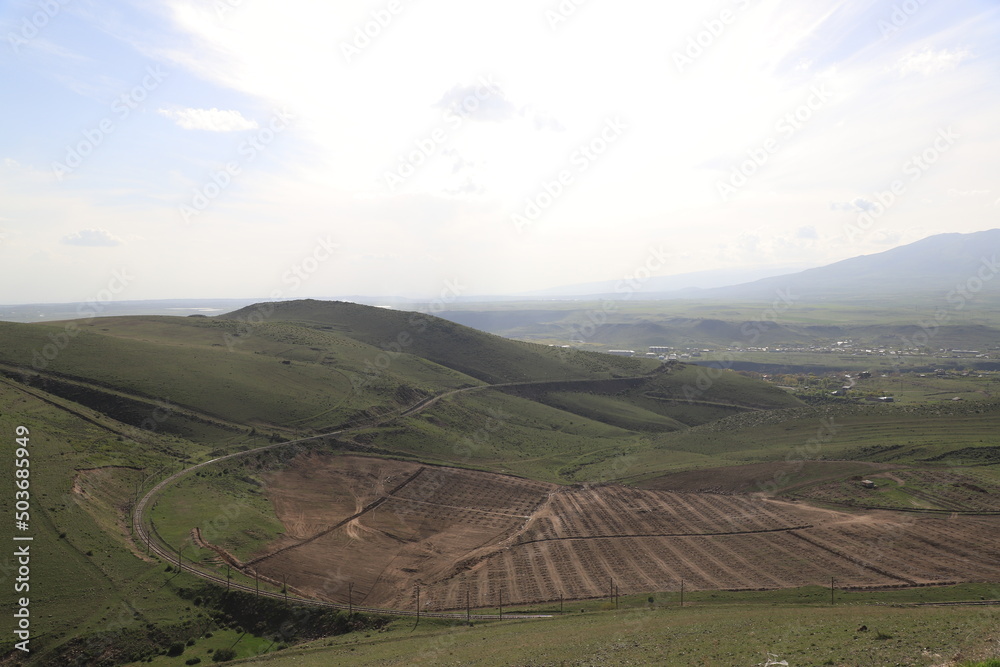 The spring landscapes with the mountains and valleys which are covered with fresh greenery, the fields are being cultivated for planting a new crop.
