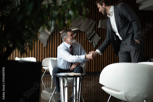 Smiling businessman greeting partner with handshake. Leadership, trust, partnership concept
