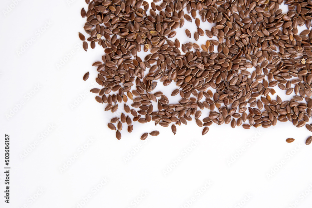 Scattered dark flax seeds on a white background, top view with a copy space for text Scattered dark flax seeds on a white background, top view with a copy space for text