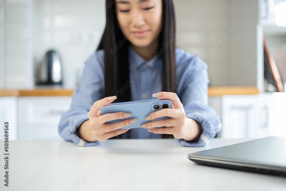 Asian gamer girl playing mobile games on modern smartphone. Happy Vietnamese female plays video game app on mobile phone in free time Asian gamer girl playing mobile games on modern smartphone. Happy Vietnamese female plays video game app on mobile phone in free time