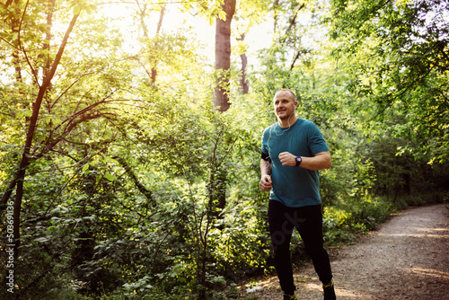 Shot of a young male runner training outdoors. Young athletic man running at park during hot summer morning. Healthy lifestyle concept.