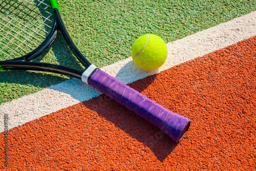 Closeup photo of a tennis ball and racket on the white line on hard tennis court. Individual sports background. photo