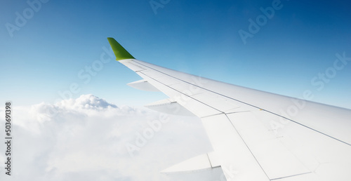 Clear blue sky with fluffy ornamental cumulus clouds, panoramic view from an airplane, wing close-up. Dreamlike cloudscape. Travel, tourism, vacations, weekend, freedom, peace, hope, heaven concepts