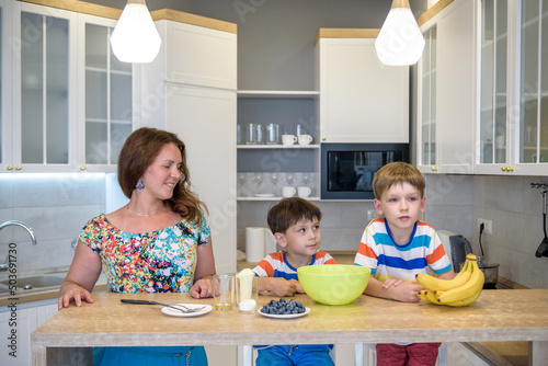 Young mother and her two kids at kitchen baking cookies