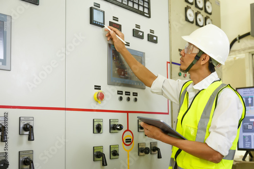 Engineer working on the checking status switchgear electrical energy distribution substation. Electrician and tool logging information in electrical switch room.