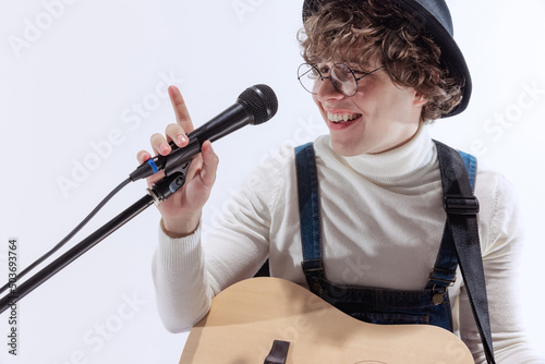 Portrait of young emotiona man, musician playing acoustic guitar and singing. Concept of art, music, style and creation photo