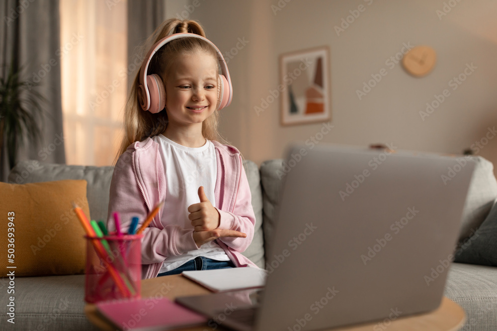 Cheerful Schoolgirl Video Calling Gesturing Thumbs Up To Laptop Indoor Cheerful Schoolgirl Video Calling Gesturing Thumbs Up To Laptop Indoor