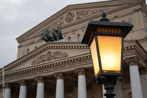 Street lantern with warm light in front of facade of Bolshoi theater in Moscow