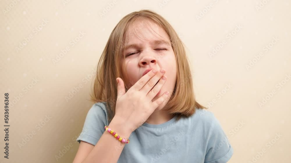 yawning cute little girl with blonde hair in a blue T-shirt. daily ...