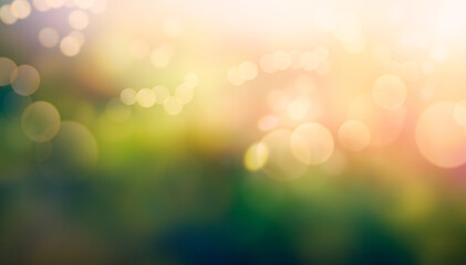 A summer sunset, sunrise background with lush green foliage and orange glow sky with blurred spring bokeh highlights.
