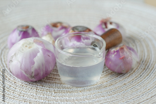 red inion oil in a container on table on white background  photo