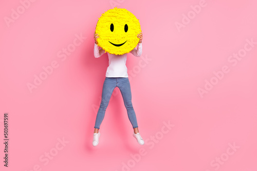 Full length photo of funky young lady jump hold smile wear shirt jeans footwear isolated on pink background