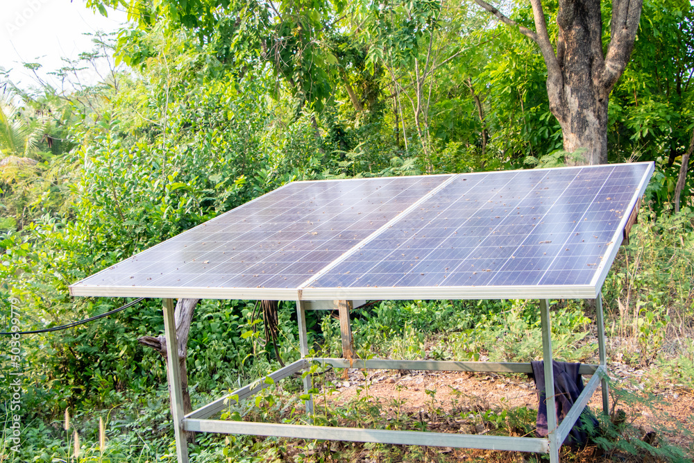 Small solar panel was place next to the well surrounded in the sun by grass. Used to generate electricity in the park to treat wastewater. Green clean Alternative power energy concept. Small solar panel was place next to the well surrounded in the sun by grass. Used to generate electricity in the park to treat wastewater. Green clean Alternative power energy concept.