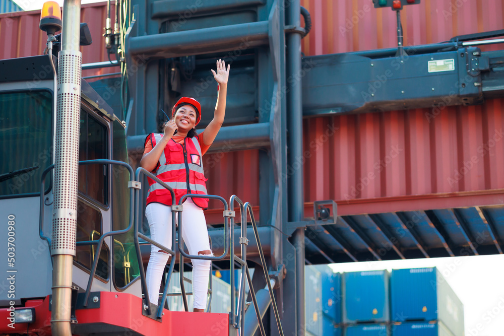 Black female dock worker control loading containers box from cargo at warehouse container yard. Marine and carrier insurance concept. logistic shipping yard