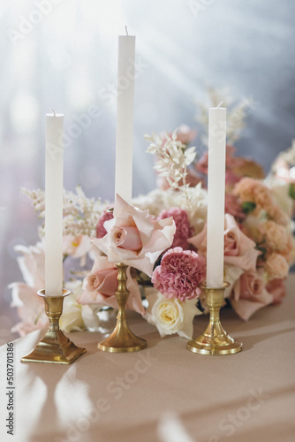 Banquet table is decorated with plates, cutlery, glasses, candles and flower arrangements © Olya