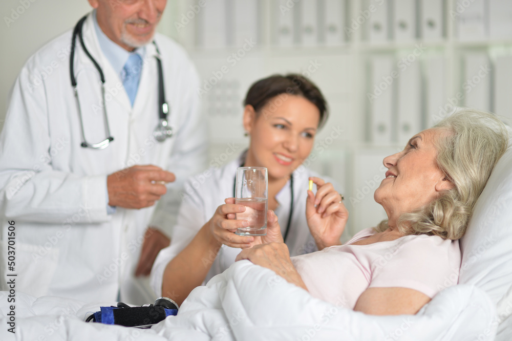 Senior woman in hospital with caring doctors