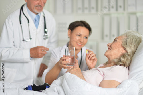 Senior woman in hospital with caring doctors