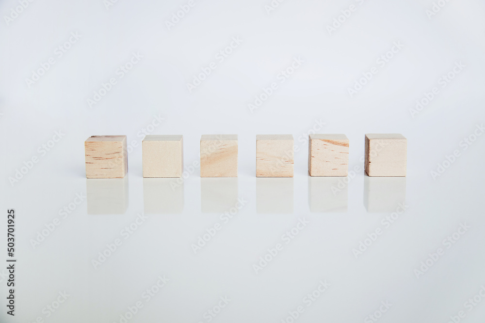 Wooden cubes arranged horizontally on white background with reflection. Conceptual and symbolic image. Copy space Wooden cubes arranged horizontally on white background with reflection. Conceptual and symbolic image. Copy space