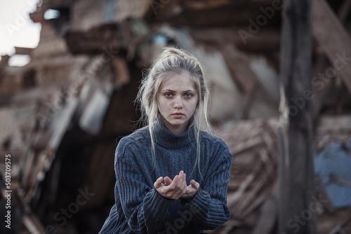 young girl screams against the background of a destroyed house. looks at the camera. military actions