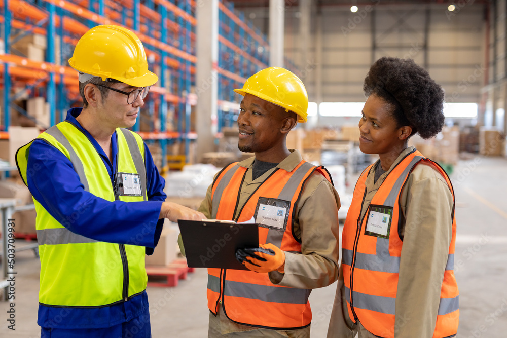 Asian mature foreman explaining over clipboard to african american young male and female workers