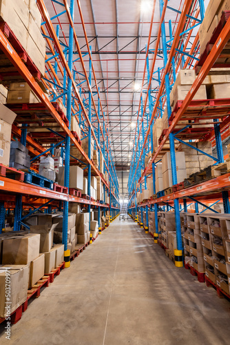 Diminishing perspective of flooring amidst shelves with cardboard boxes in distribution warehouse photo