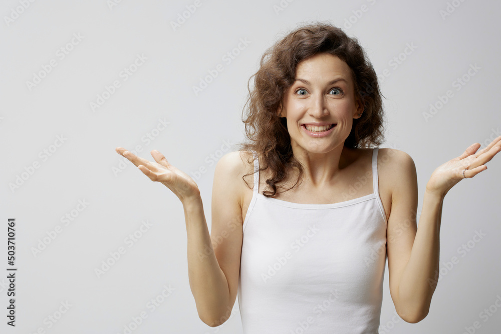 Cheerful surprised excited curly beautiful woman in basic white t-shirt raise hands up won a million posing isolated on over white background. People Emotions Lifestyle concept. Copy space Cheerful surprised excited curly beautiful woman in basic white t-shirt raise hands up won a million posing isolated on over white background. People Emotions Lifestyle concept. Copy space