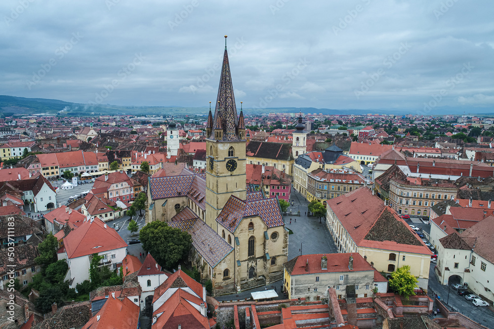 Landmarks of Romania. Aerial view of the old center of Sibiu city at the bottom of Fagaras Mountains during a cloudy sky day. Evangelical Cathedral in frame.