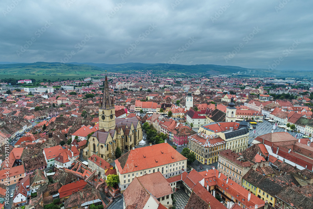 Landmarks of Romania. Aerial view of the old center of Sibiu city at the bottom of Fagaras Mountains during a cloudy sky day. Evangelical Cathedral in frame.