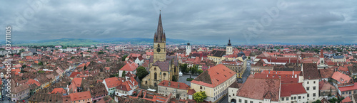 Landmarks of Romania. Aerial view of the old center of Sibiu city at the bottom of Fagaras Mountains during a cloudy sky day. Evangelical Cathedral in frame.