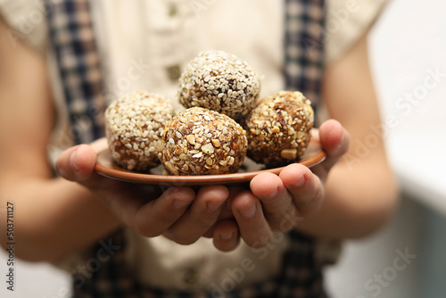 Child holding a plate full of energy balls close up.