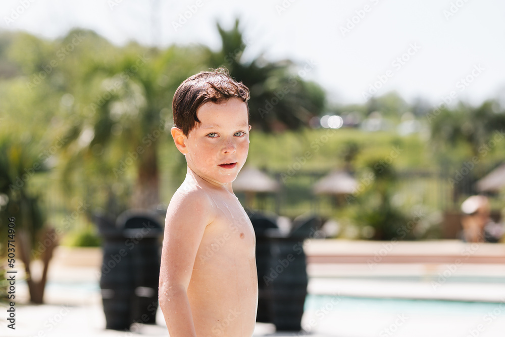 Little boy standing near swimming pool on sunny day Little boy standing near swimming pool on sunny day