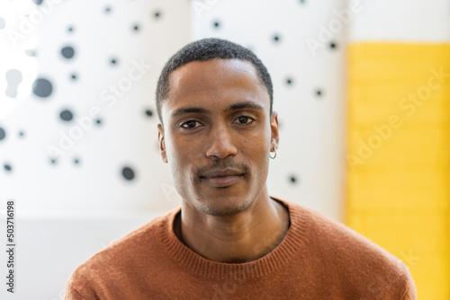 Young Moroccan man with magnetic gaze looking at the camera - Studio portrait of charming young middle eastern man against a yellow and white background - Copy space for text