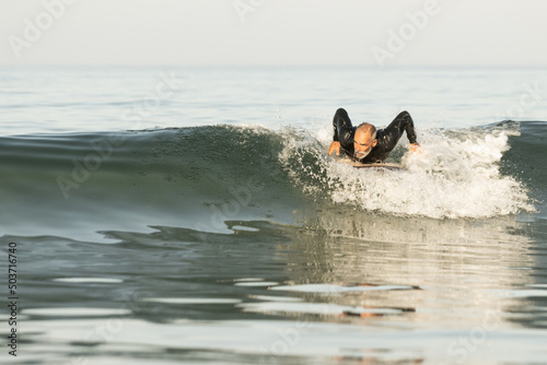 Photography Middle-aged African male surfing on the waves, Lisbon, Portugal