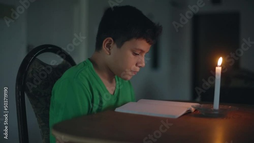 child sitting reading at the table with candlelight photo