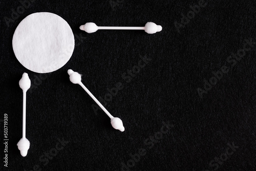 top view of ear sticks near white cotton pad on black background.