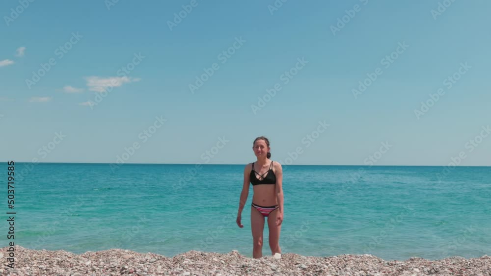Girl in a swimsuit on the beach, a woman on a summer vacation on the sea coast Girl in a swimsuit on the beach, a woman on a summer vacation on the sea coast