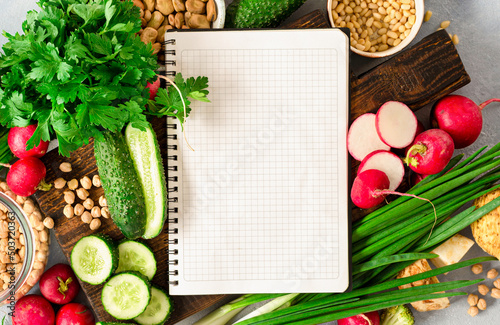 Diet plan concept. Healthy food ingredients. Blank notebook with fresh vegetables, herbs, legumes and nuts top view