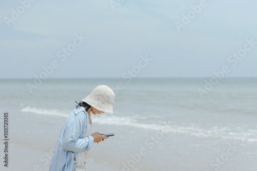 Beautiful beautiful young woman using mobile phone at beach. woman standing take photograph sandy beach