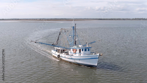 Low aerial view of a shrimp boat pulling nets off the coast of South Carolina, USA.