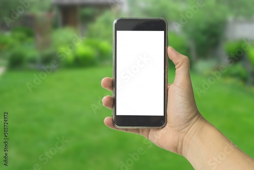 man holding phone, right hand mockup in park outdoors, has green wood background, isolated screen insert display