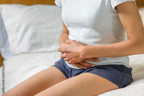 Woman holding stomach with cramp or pain photo