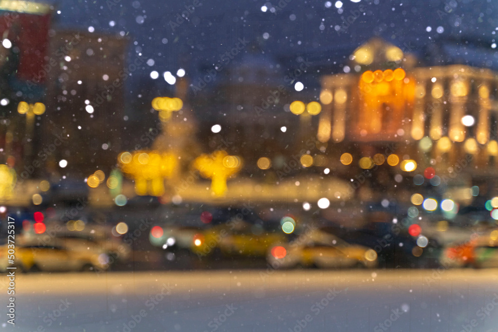 blurred background with bokeh. road traffic in a big city on a winter night in heavy snow