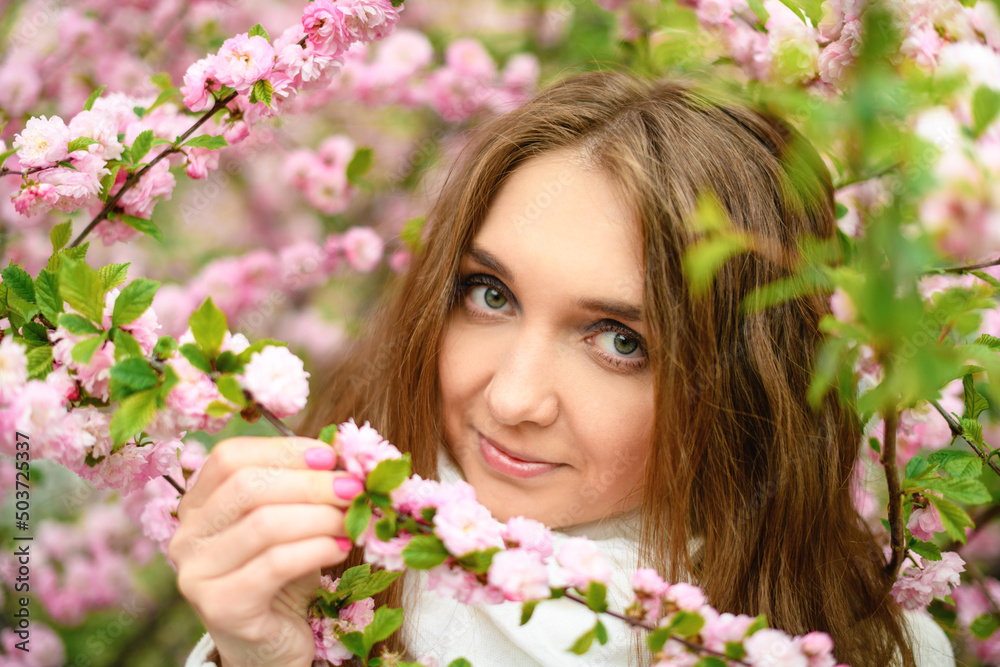 Beautiful girl and blooming garden, portrait. Girl in white coat with blooming sakura, apple tree Beautiful girl and blooming garden, portrait. Girl in white coat with blooming sakura, apple tree