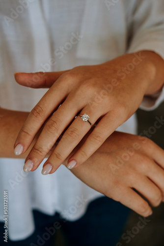Fototapeta Naklejka Na Ścianę i Meble -  Golden Ring on a female hand, diamonds Diamond ring in hands of young lady. Close-up photo shoot