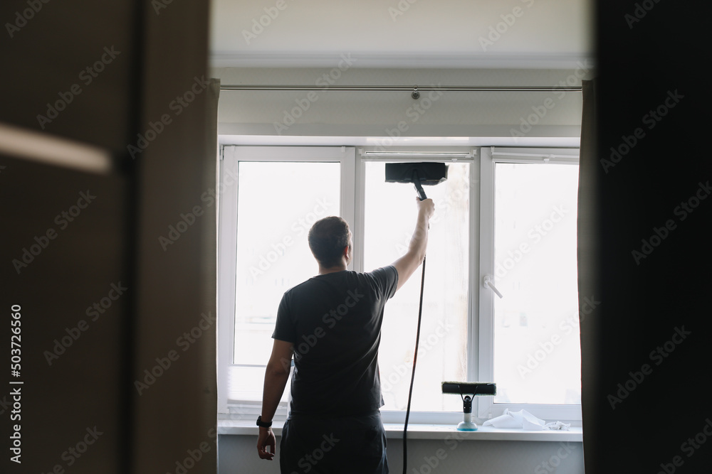 Man washing and cleaning window at home. Housework and housekeeping, home hygiene Man washing and cleaning window at home. Housework and housekeeping, home hygiene